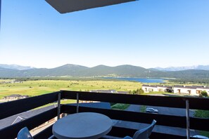 Ein Balkon mit Tisch und Stühlen, der einen schönen Panoramablick auf Berge und einen See bietet.