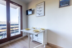 Ein Zimmer mit Esstisch für vier Personen, einem Wand-Fernseher und einem Bild an der Wand.