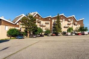 Ein mehrgeschossiges Wohnhaus mit Balkonen, einem Parkplatz und blauem Himmel.