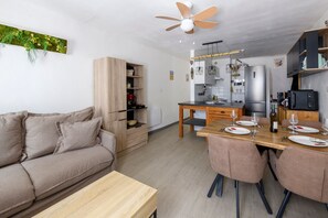 A modern kitchen with a dining area, wooden furniture, and a ceiling fan. - La Maison Gecko Montfrin - Proche du Pont du Gard (Montfrin)