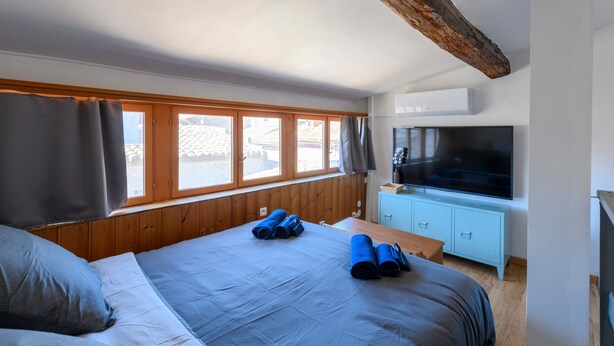 Un dormitorio con una cama, un televisor y una ventana.