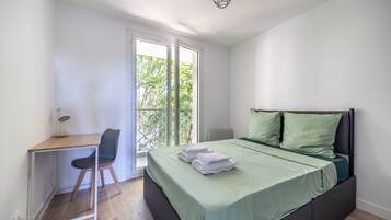 Un dormitorio con cama, escritorio y silla.