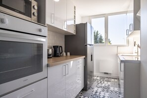 A modern kitchen with a microwave, oven, refrigerator, and coffee maker. - La Parenthèse Toulousaine - À 200 m du métro (Toulouse)