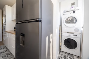 A compact kitchen with a stainless steel refrigerator, a built-in washing machine, and a microwave. - La Parenthèse Toulousaine - À 200 m du métro (Toulouse)