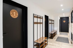 A hallway with black doors, wooden benches, and metal coat hooks. - Suite Briance - Joli duplex pour 4 avec balcon (Saint-Chaffrey)