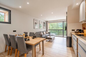 A modern living space with a dining area, a sofa, and a kitchen. - Suite Briance - Joli duplex pour 4 avec balcon (Saint-Chaffrey)
