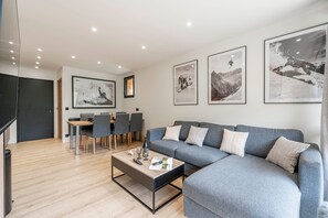 A modern living room with a grey sofa, a coffee table, and framed pictures on the wall. - Suite Briance - Joli duplex pour 4 avec balcon (Saint-Chaffrey)