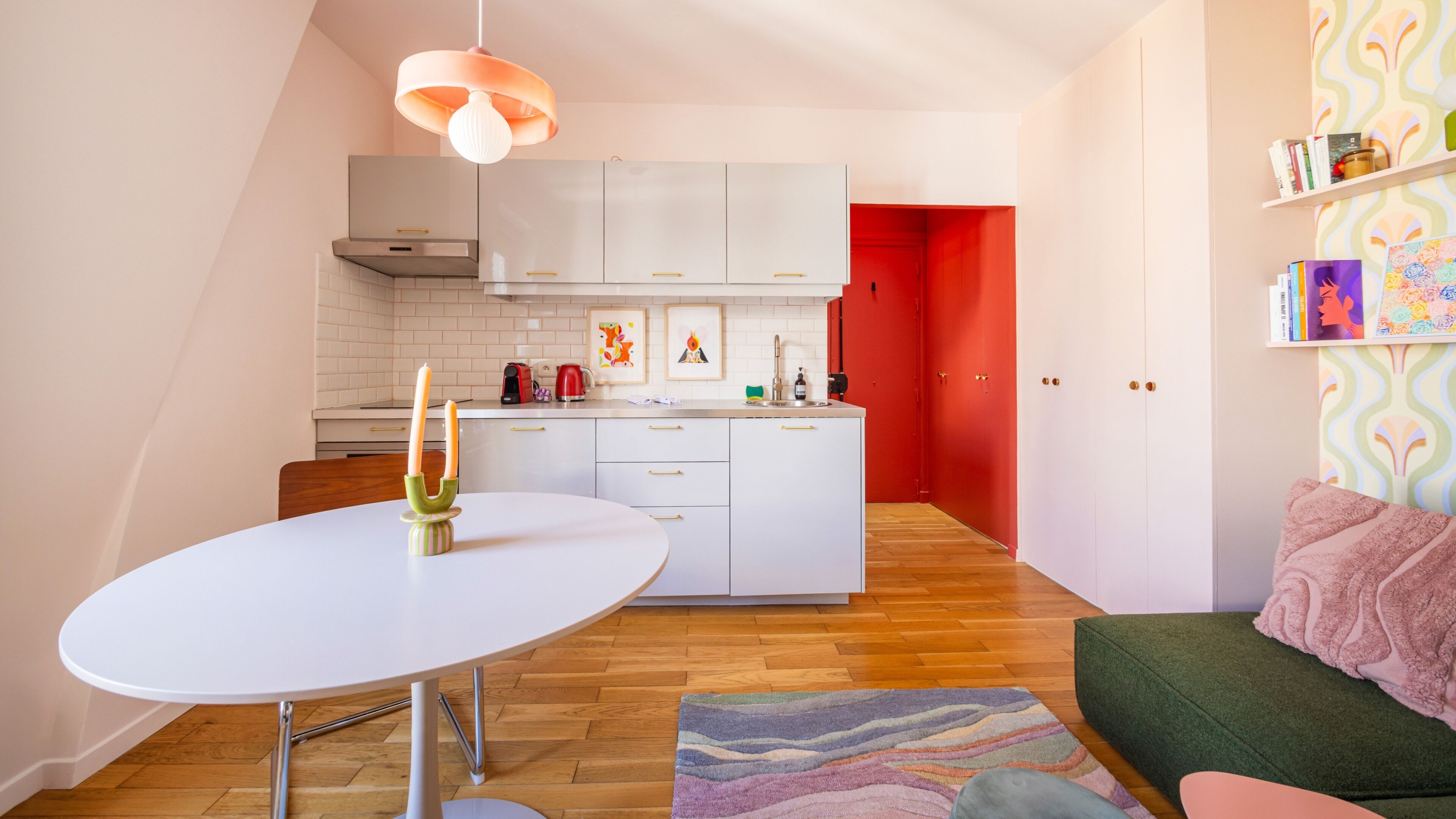 A compact kitchen with white cabinets, a dining table, and a red door.