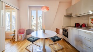 Een moderne keuken met een ronde tafel, stoelen en een hanglamp.