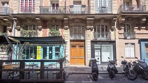 Una hilera de edificios con una puerta de madera, un letrero que dice 'Imaya Concept' y scooters estacionados.