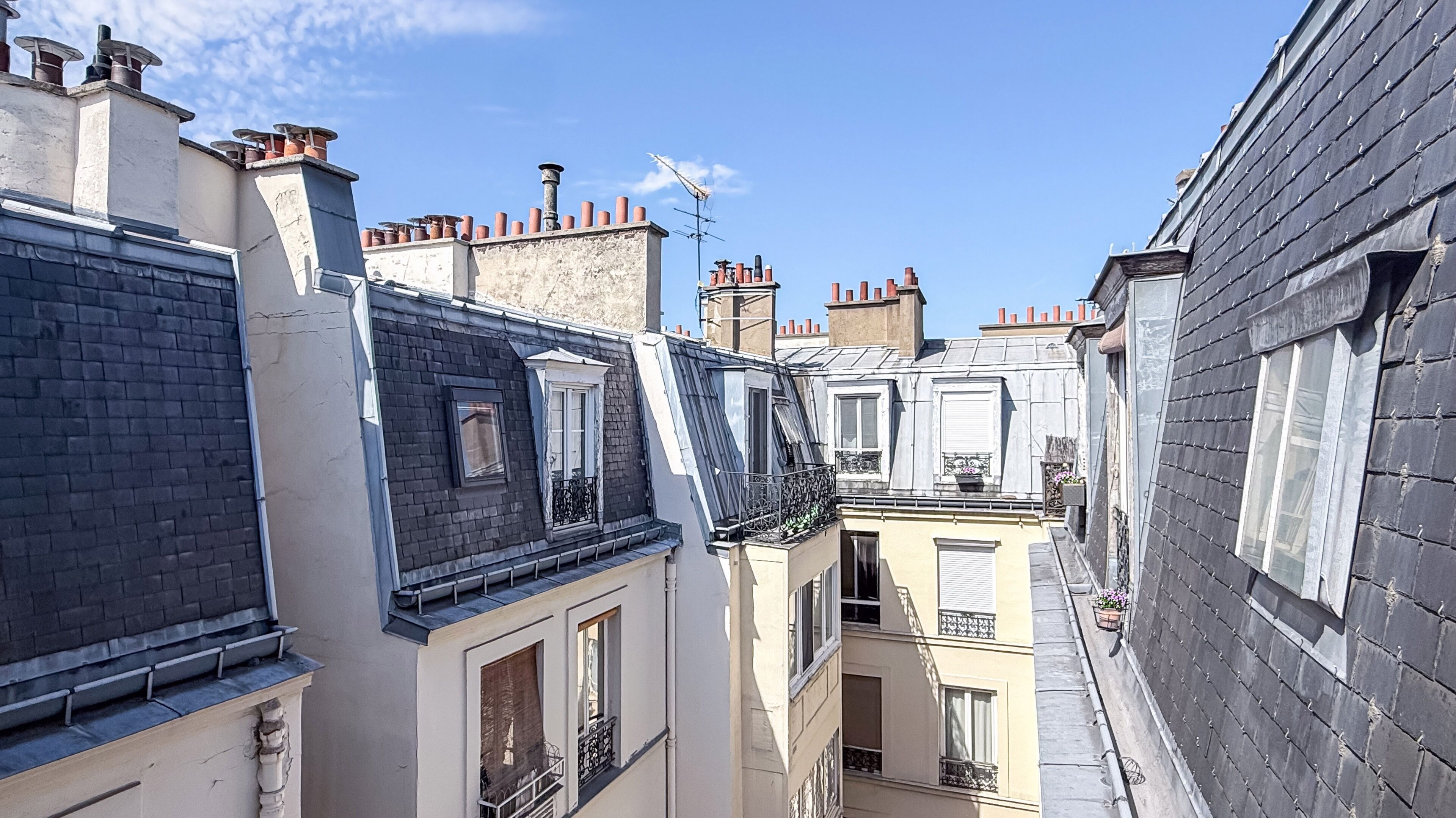 Une rue étroite en milieu urbain, bordée d’immeubles d’habitation construits très près les uns des autres, caractérisée par des toits à forte pente et de petits balcons.