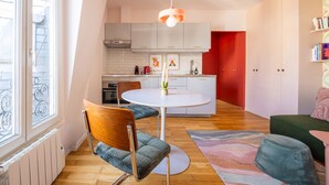 Una cocina moderna con armarios blancos, una mesa redonda y una pared de acento roja.
