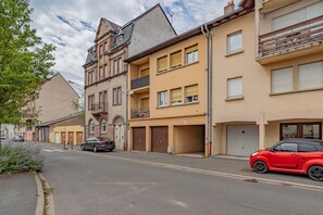 A street with residential buildings, a red car parked on the side, and a grey car in the distance. - Le Havre de Pin’s - À 600 m de la gare (Sarrebourg)
