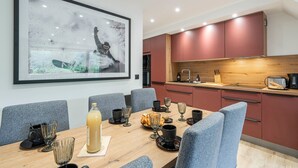 A modern dining area with a wooden table, grey chairs, and a large framed picture on the wall. - Suite Cucumelle - Beau Duplex pour 6 avec balcon (Saint-Chaffrey)