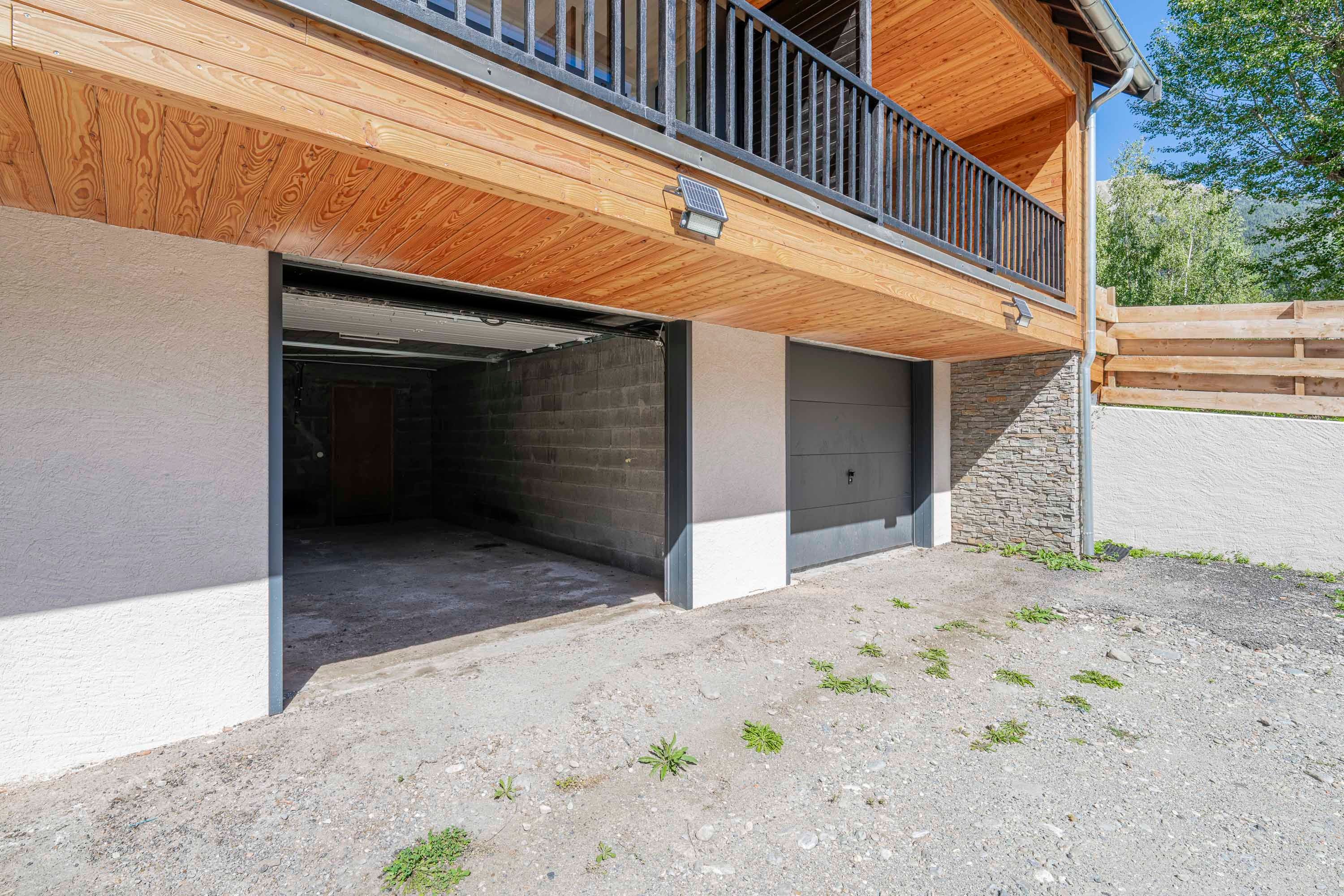 Ein Gebäude mit einem Holzbalkon, einer Garage und einer Steinmauer.