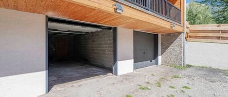 Ein Gebäude mit einem Holzbalkon, einer Garage und einer Steinmauer.