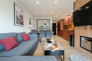 Una sala moderna con un sofá gris, una mesa de centro y un comedor con sillas.
