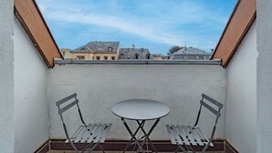 A small balcony with two metal chairs and a table, overlooking a row of buildings. - La Réserve de Fathala - À 500 m de la gare (Sarrebourg)