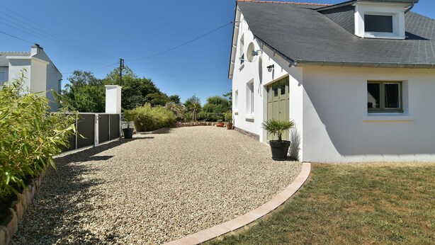 A residential property with a gravel driveway, a white house with a grey roof, and a small garden area. - Fargesia - Jolie maison avec jardin, proche plage (Fréhel)