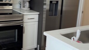 A kitchen with a microwave, oven, coffee maker, refrigerator, and a sink. - Cozy 1-Bedroom Condo minutes from the Beach, Kill Devil Hills with AC (Kill Devil Hills)