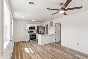 Una cocina moderna con armarios blancos, horno empotrado, microondas y un refrigerador de acero inoxidable.