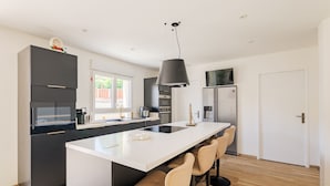 Eine moderne Küche mit Kochinsel, Barhocker und einer Pendelleuchte.