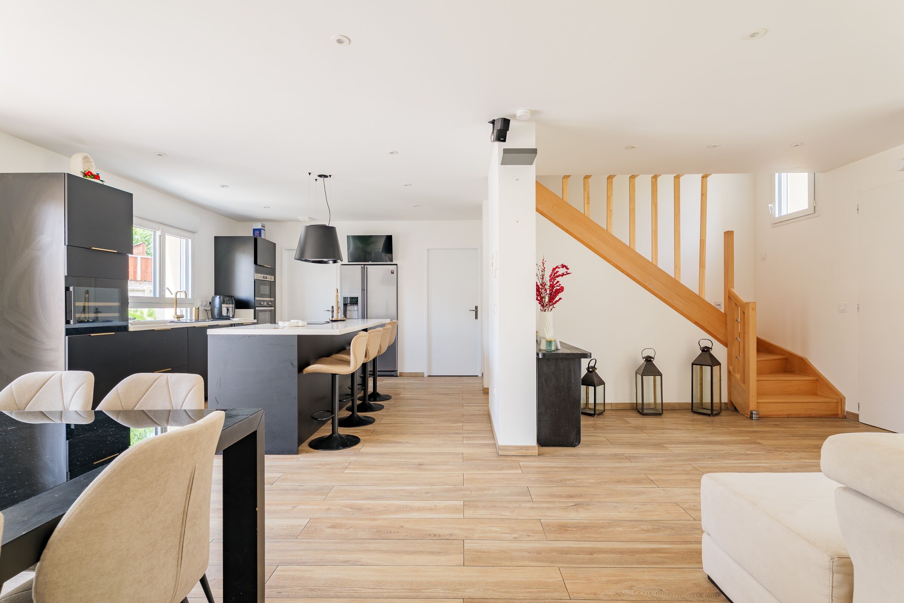 A modern kitchen with a central island, bar stools, and a dining area with a table and chairs.