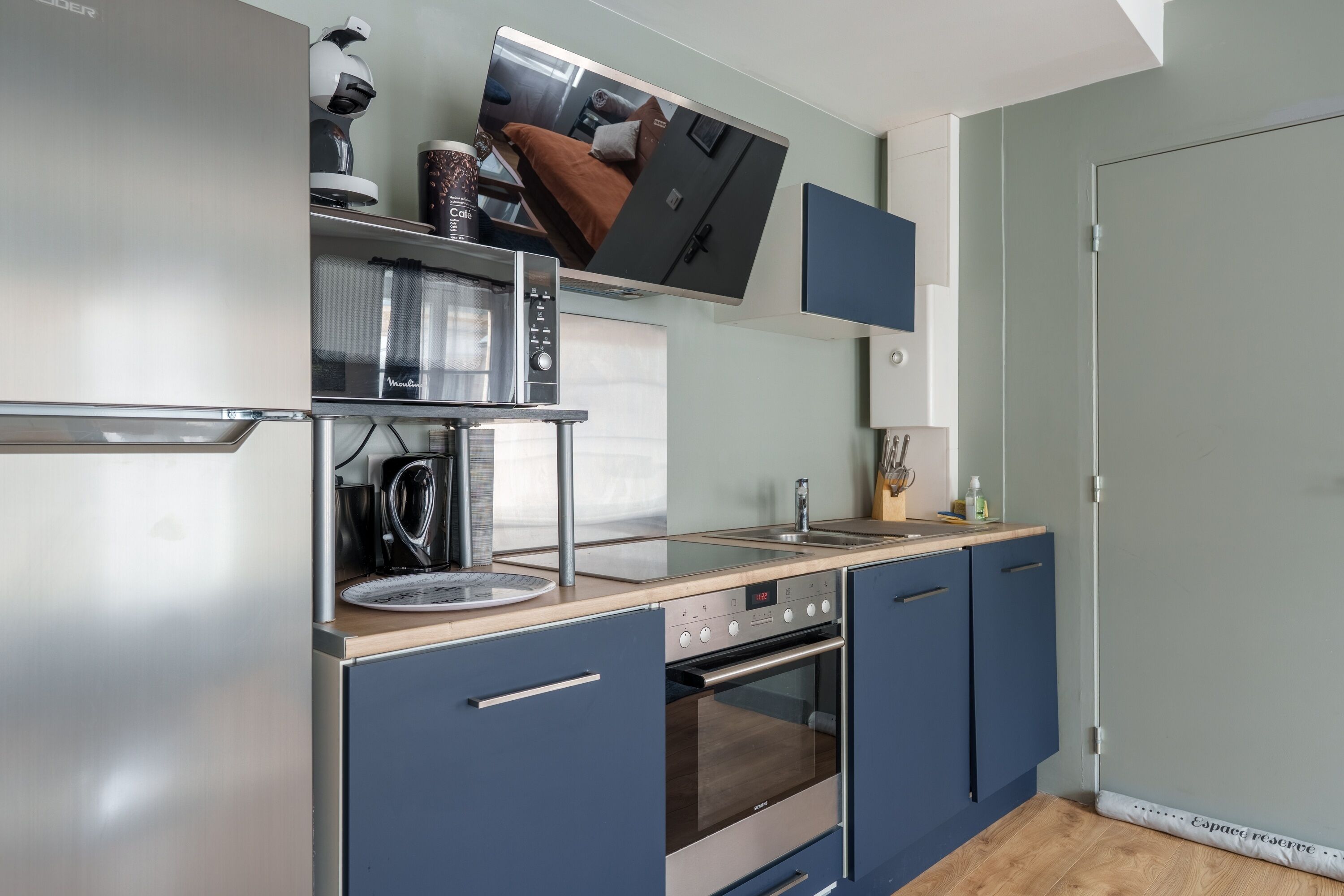 A modern kitchen with a built-in oven, microwave, and coffee machine.