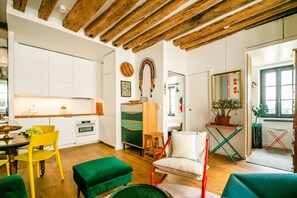 Una cocina moderna con vigas de madera, un comedor con sillas amarillas y un otoman verde.