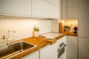 A modern kitchen with white cabinets, a wooden countertop, a stainless steel sink, and an oven. - Marais Colors - À 750 m de la place de la Bastille (Paris)