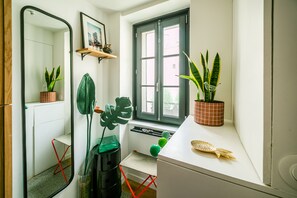 A compact bathroom with a window, a mirror, a sink, and several potted plants. - Marais Colors - À 750 m de la place de la Bastille (Paris)