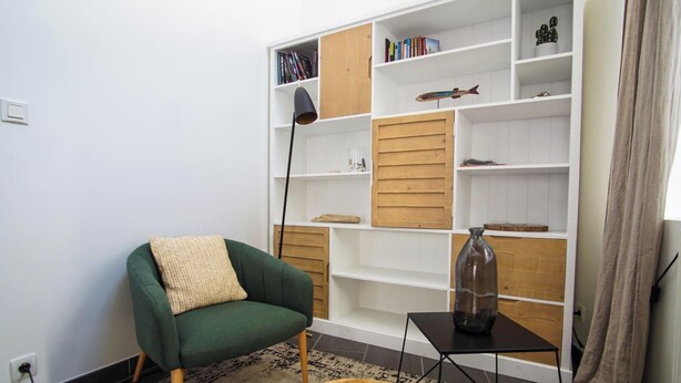 A living room with a green armchair, a small table with a vase, and a bookshelf with various items. - -BLOOM- TOWNHOUSE WITH GARAGE, SHARED COURTYARD (Concarneau)