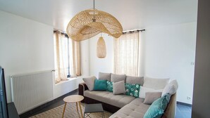 A modern living room with a sofa, a small round table, and a hanging light fixture. - -BLOOM- TOWNHOUSE WITH GARAGE, SHARED COURTYARD (Concarneau)