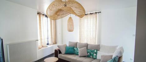 A modern living room with a sofa, a small round table, and a hanging light fixture.