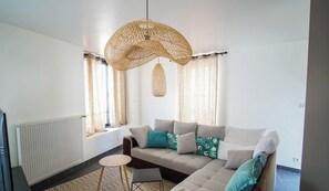 Ein modernes Wohnzimmer mit einer Couch, einem kleinen runden Tisch und einer Pendelleuchte.