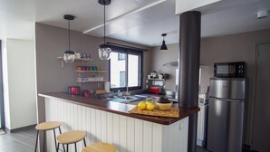 A modern kitchen with a central island, stainless steel appliances, pendant lighting, and a view to the outside. - -BLOOM- TOWNHOUSE WITH GARAGE, SHARED COURTYARD (Concarneau)