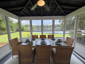 Ein Wintergarten mit Tisch für sechs Personen, Korbstühlen und Seeblick.