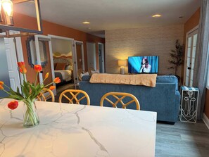 A modern living area with a sofa, television, and a dining table with chairs.