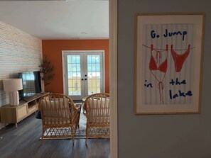 Ein Wohnzimmer mit Korbstühlen, einem Fernseher und einem gerahmten Kunstwerk an der Wand.