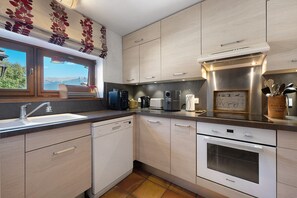 Eine moderne Küche mit eingebautem Geschirrspüler, einem Herd und einem Fenster mit Blick ins Freie.