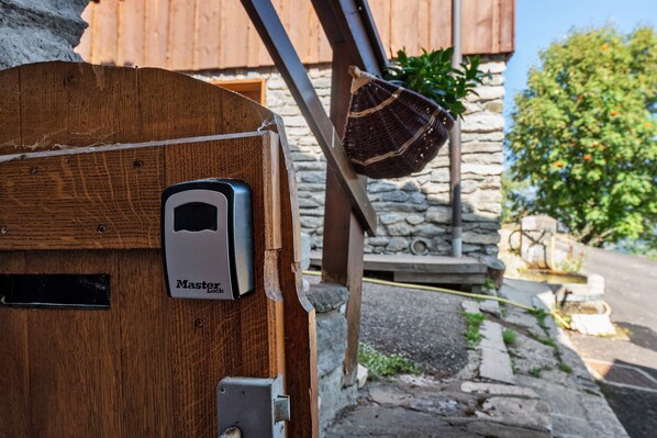 Una puerta de madera con un dispositivo de bloqueo Master Lock, una pared de piedra y una estructura de madera al fondo.