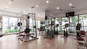 Un'ampia palestra con diverse attrezzature per esercizi, ampie finestre e un pavimento uniforme.