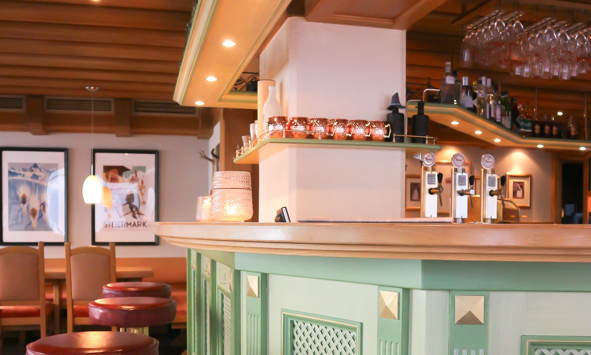 A bar area with stools, a counter, and a shelf with bottles.