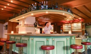 Un'area bar con un bancone curvo, sgabelli e un barista.