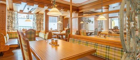A dining area with wooden furniture, including a table and benches, and pendant lighting.