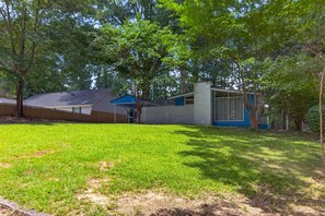 A house with a blue exterior, a covered porch, and a yard with grass and trees. - Beautiful Bungalow near Buckhead (Doraville)