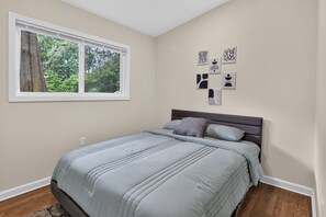 A bedroom with a bed, a window, and wall art. - Beautiful Bungalow near Buckhead (Doraville)