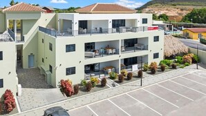 Et hotel med flere etager, altaner, en parkeringsplads og en bindingsværksbygning i baggrunden.