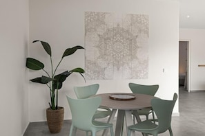 Un coin repas avec une table ronde, quatre chaises et une plante en pot.