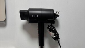 A black hairdryer with a cord plugged into a wall socket. - Private Movie Theater in Calais • XXL Screen • Immersive sound (Calais)